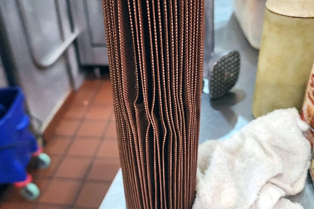 Pleated water filter cartridge discoloured deep brown across every pleat after being left in service far past its capacity