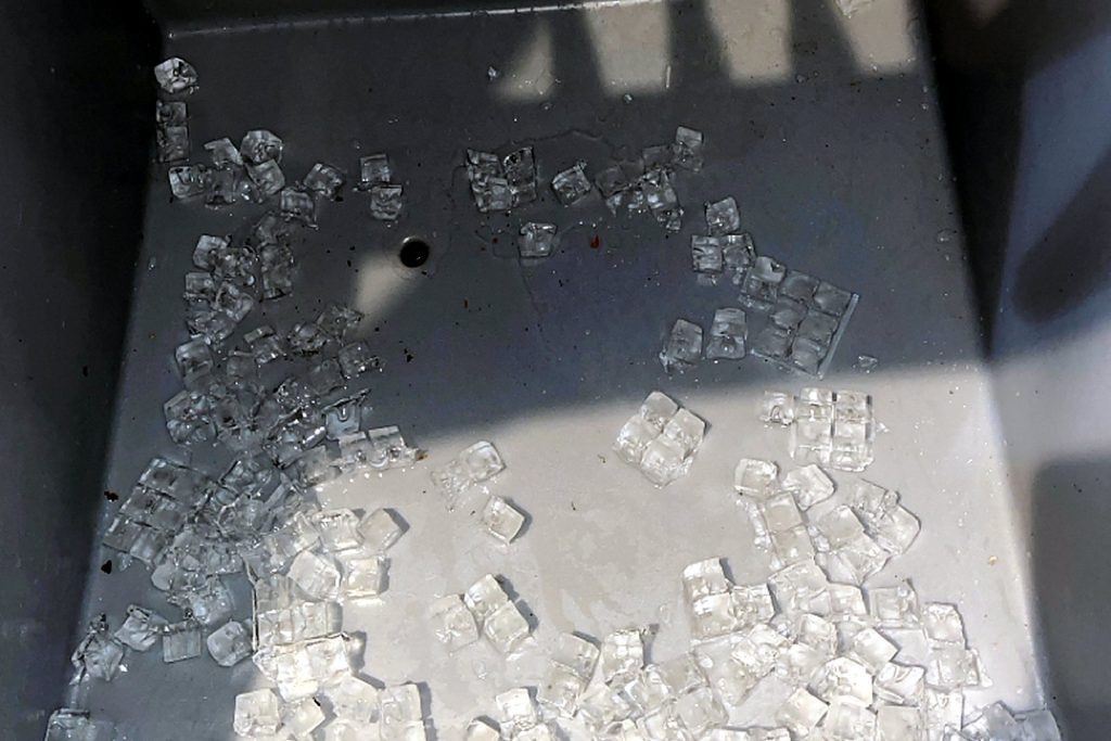 Commercial ice storage bin holding only a thin scattering of small cubes partway through a service day