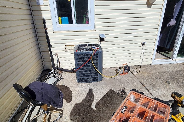 Daikin outdoor condensing unit set level on pavers beside a house with clear space around it for airflow