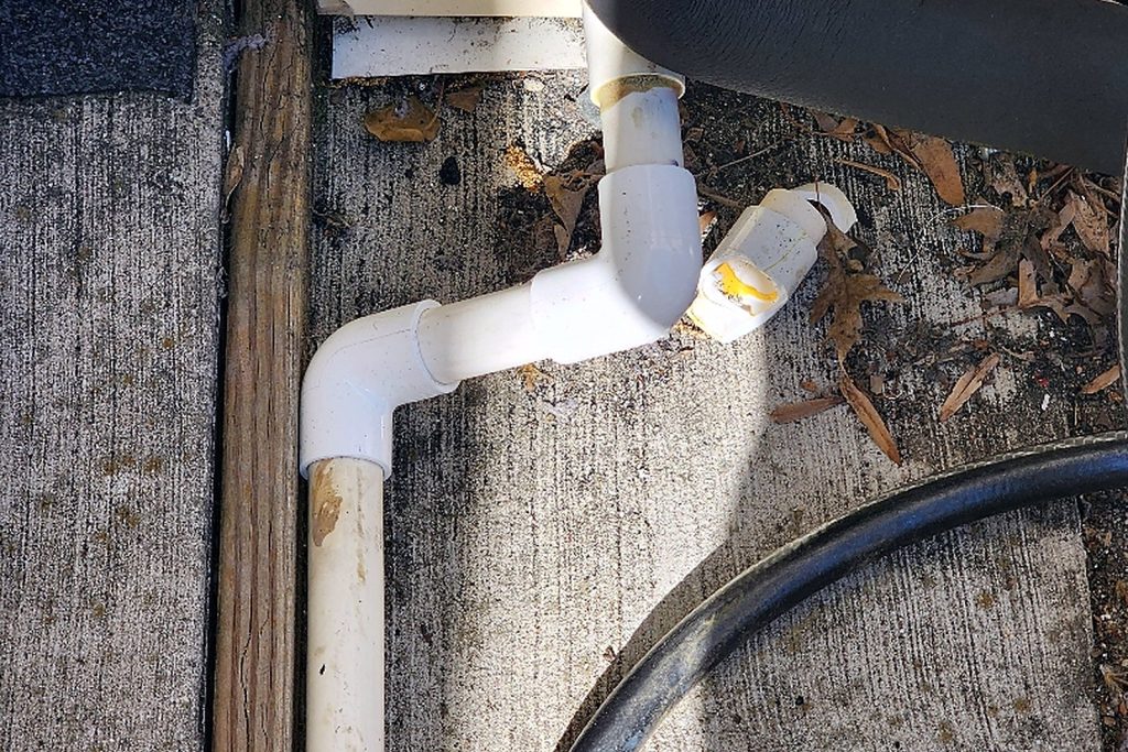 Refrigerant line set insulated and run inside a protective cover down the exterior wall of a house