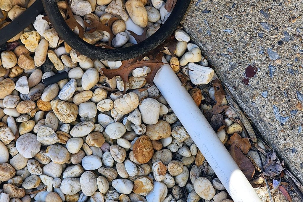 Condensate line piped and terminated away from the building foundation over a bed of river rock