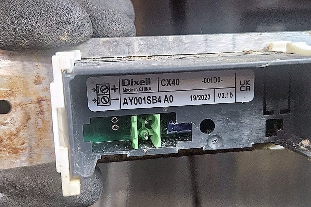 Dixell CX40 refrigeration control module held in a gloved hand, showing its part label and circuit board