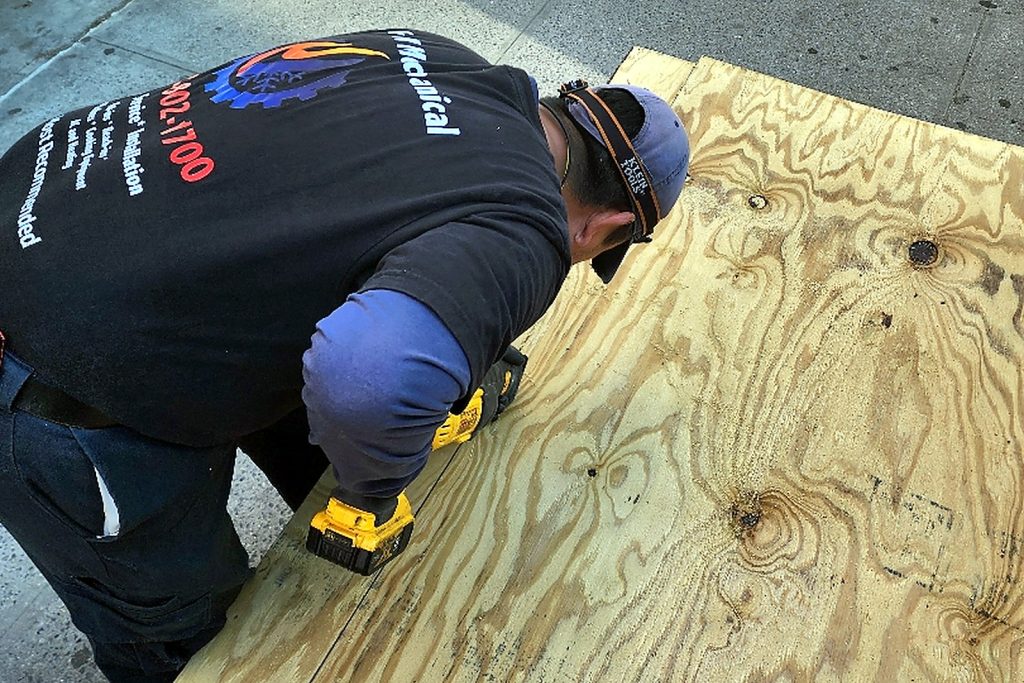 Technician fitting a plywood subfloor inside a walk-in freezer shell during a floor build