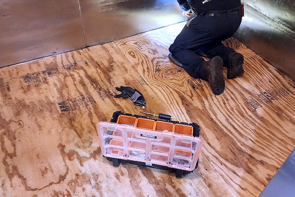 Rigid insulation boards staged over the plywood subfloor of a walk-in freezer