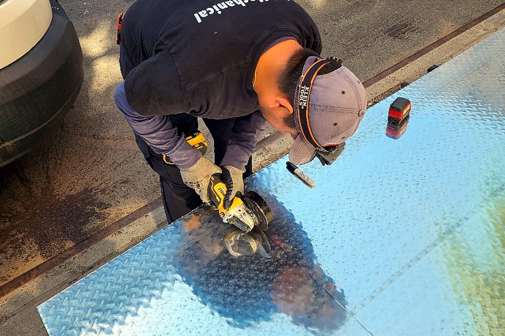 Technician laying diamond-plate decking over insulation board inside a walk-in freezer