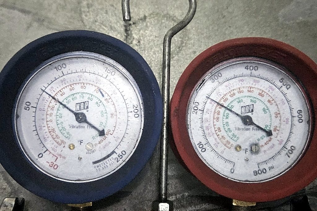 Refrigerant manifold gauges connected to the outdoor condensing unit showing normal operating pressures