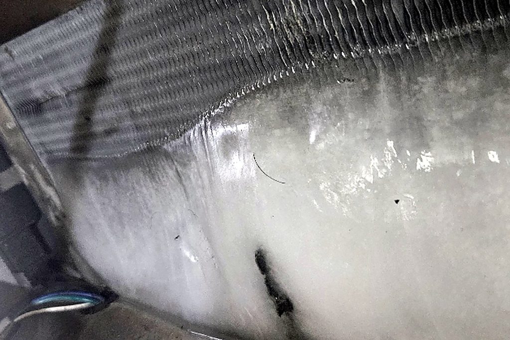 The evaporator coil behind the grille, iced solid from top to bottom.