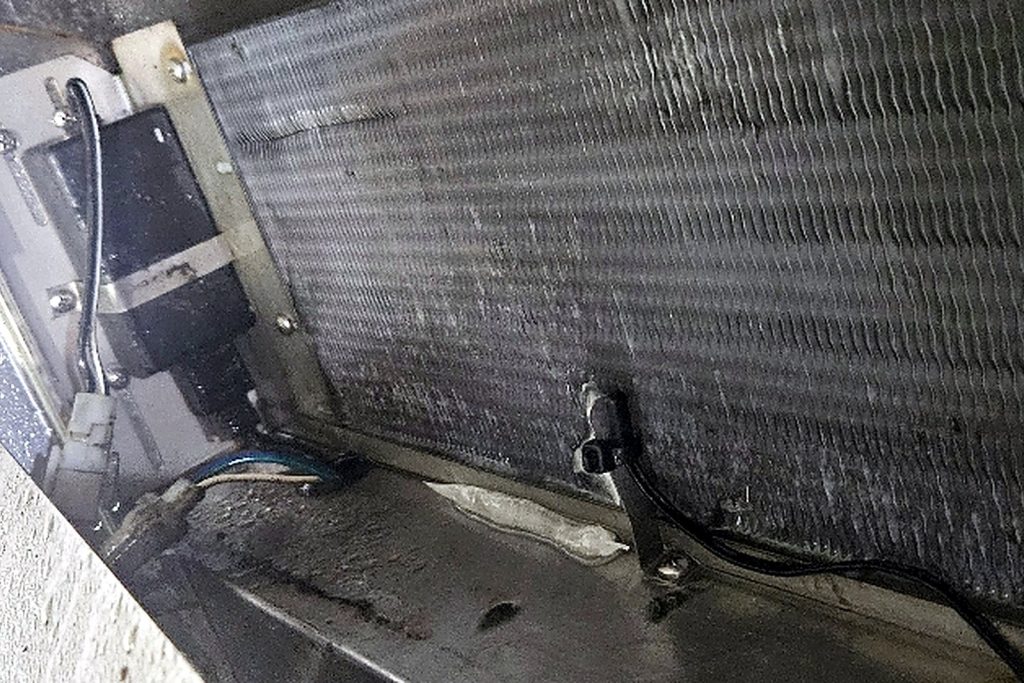 The same coil after thawing: wet, clear and moving air again, with the controller probe visible at the coil face.