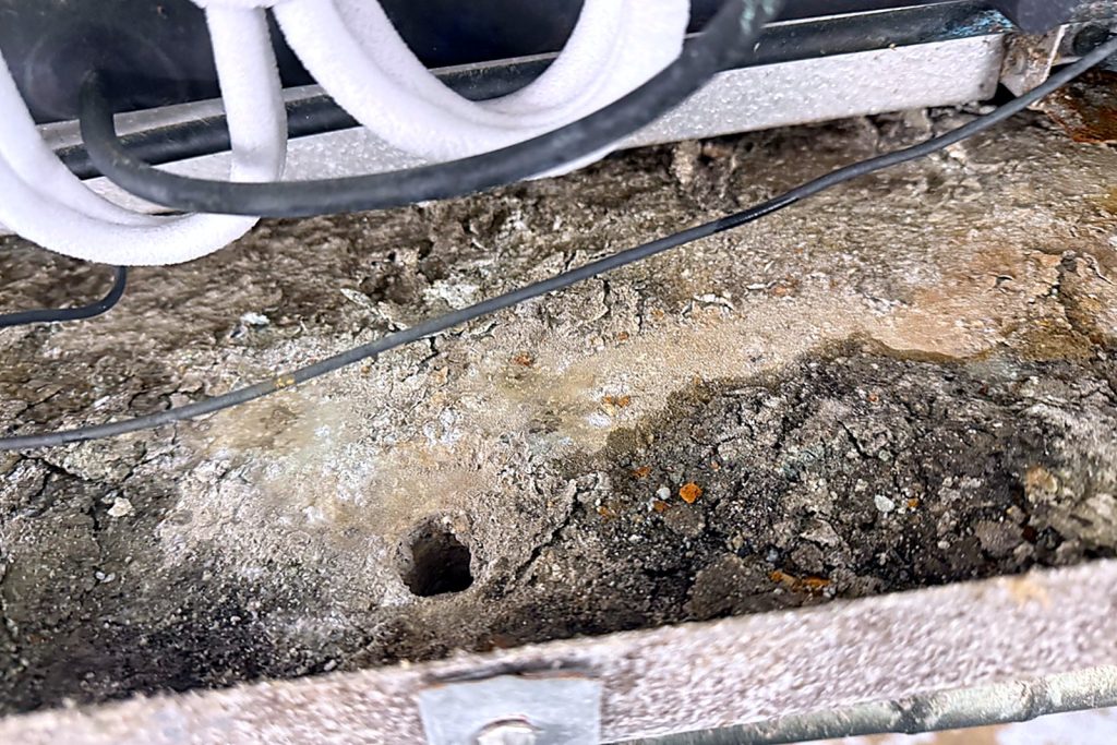 Inside the drain pan: grey sludge up to the outlet, which is almost closed.