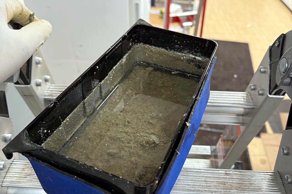 The pan out of the unit and on the ladder, full of the same sludge.