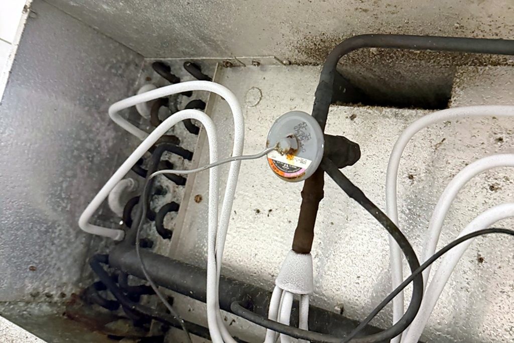 The new expansion valve brazed in at the coil inlet, bulb capillary routed to the suction line and fresh insulation on the lines.