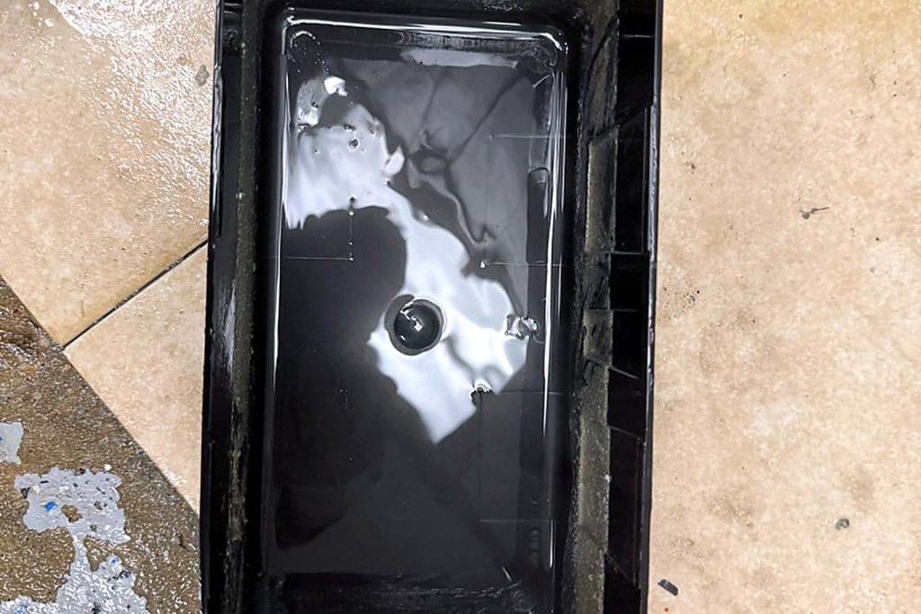 A drain pan after scrubbing: clean, with water running to the outlet instead of over the edge.