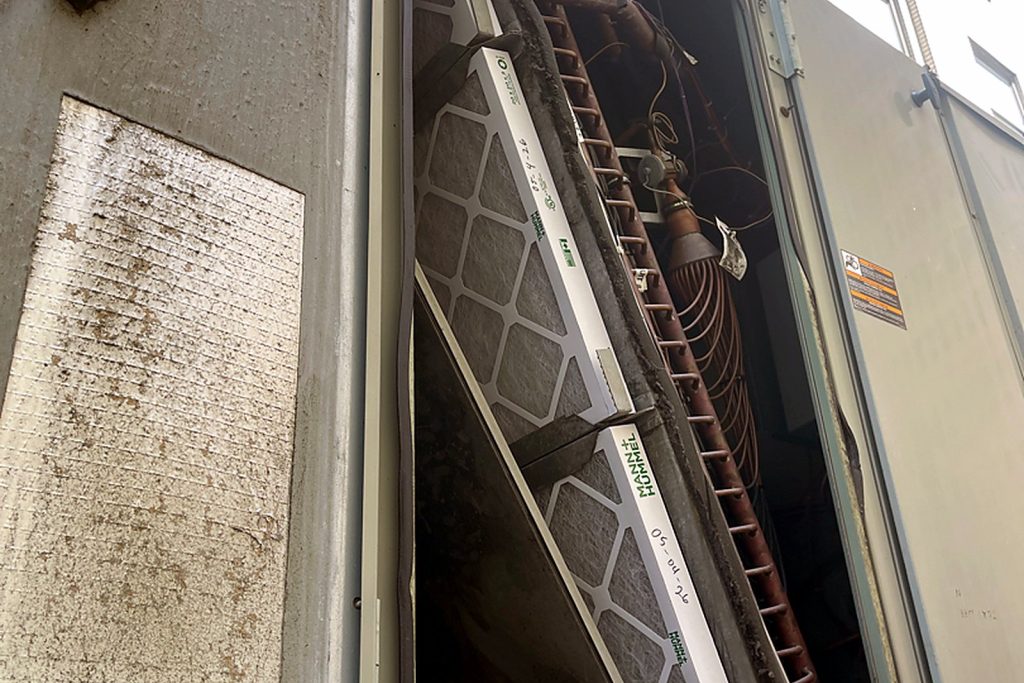 Open access door on a rooftop unit showing the filter rack and the evaporator section behind it