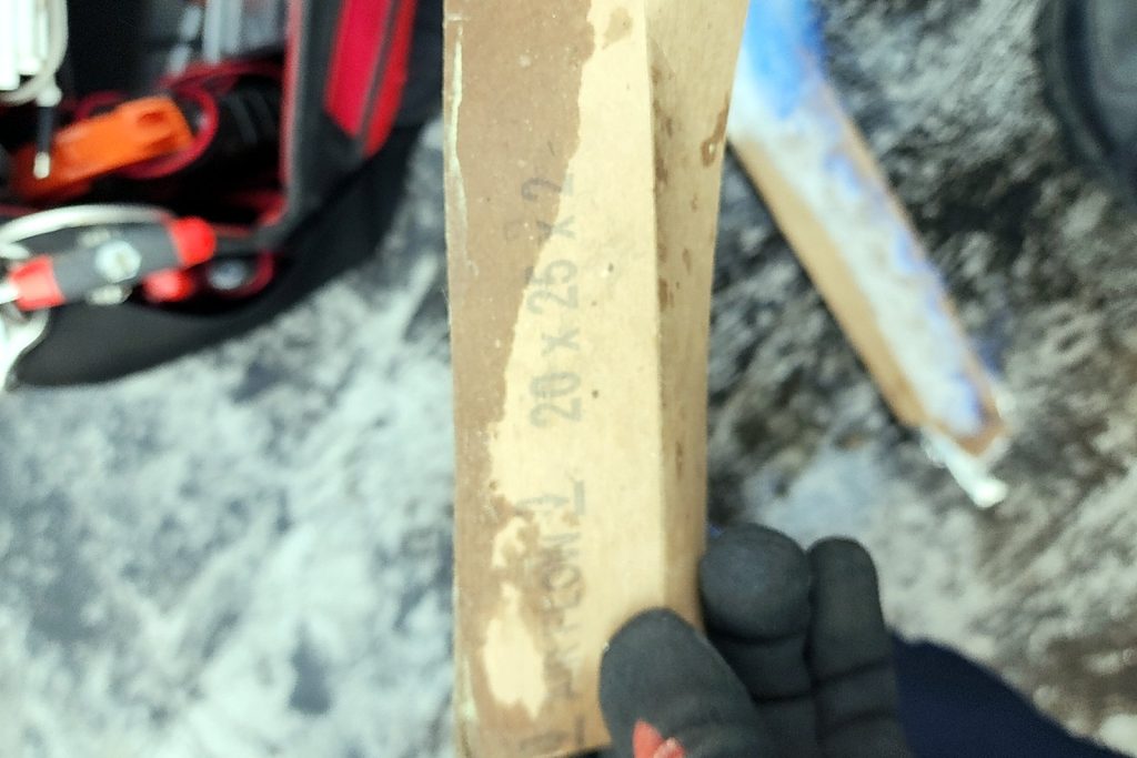 Edge of a used 20x25x2 pleated filter held up beside the unit, marked with its size