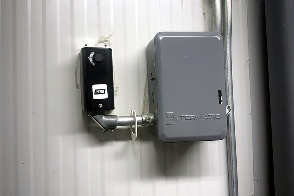 New Penn temperature control mounted beside an Intermatic defrost timer box inside a walk-in, connected with conduit