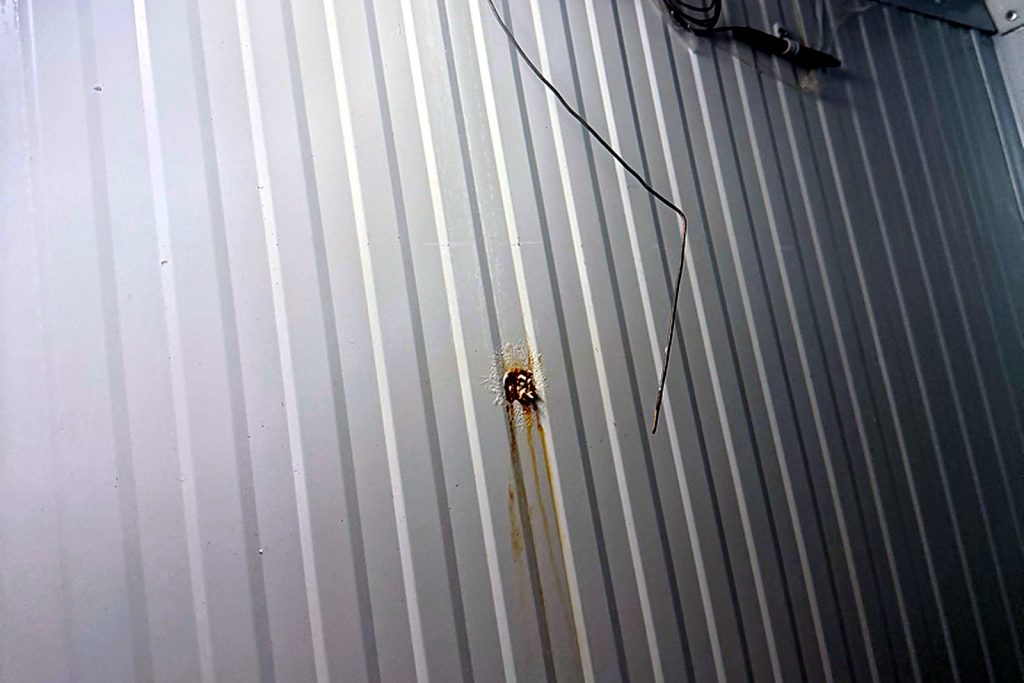 Walk-in wall panel with a rust stain where the old thermostat was mounted and the capillary bulb wire tacked along the wall