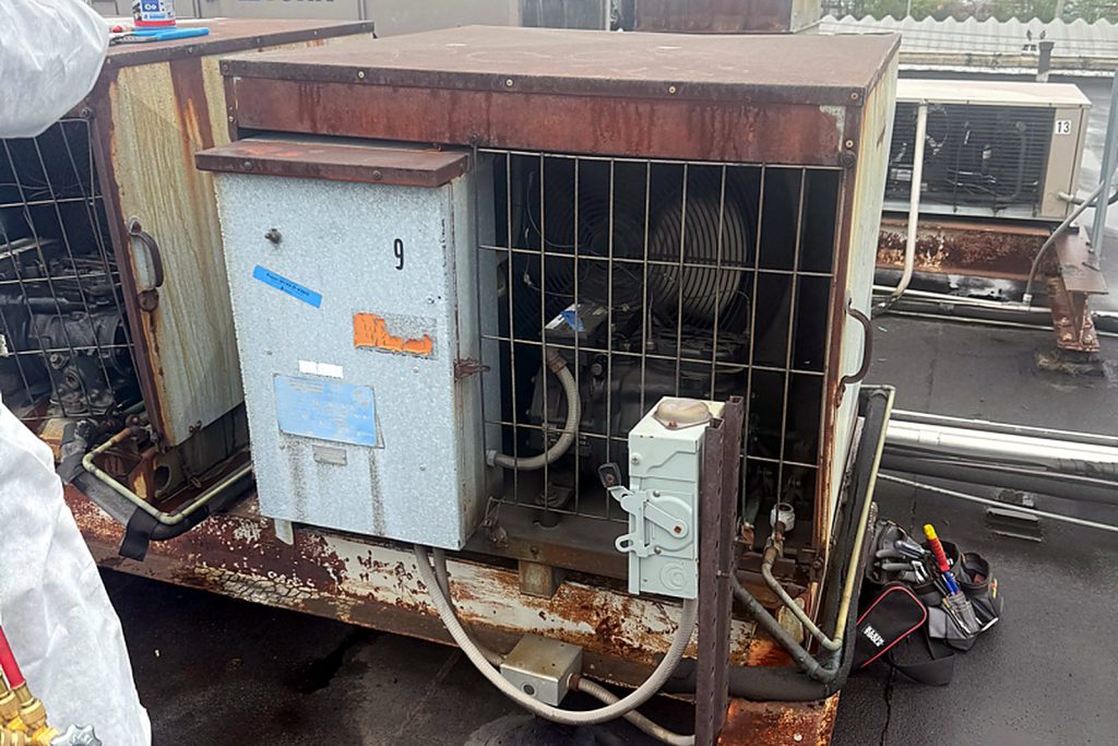 The condensing unit that feeds the walk-in, on the roof, where the day started. Older cabinet, running compressor, gauges on.